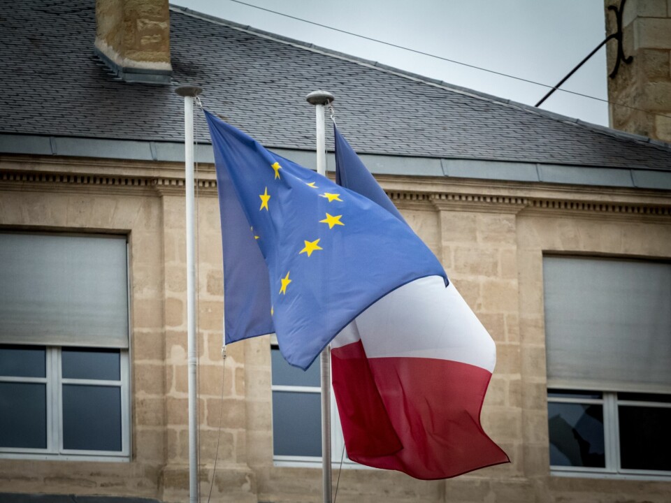 The French and EU flags flying in front of an old building