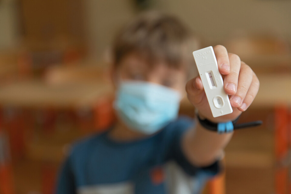 A young boy holds up a negative Covid self-test