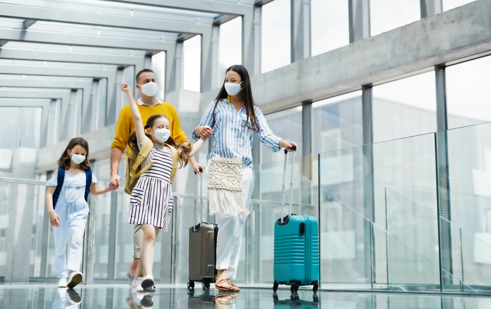 An image of a family of four walking through an airport wearing masks