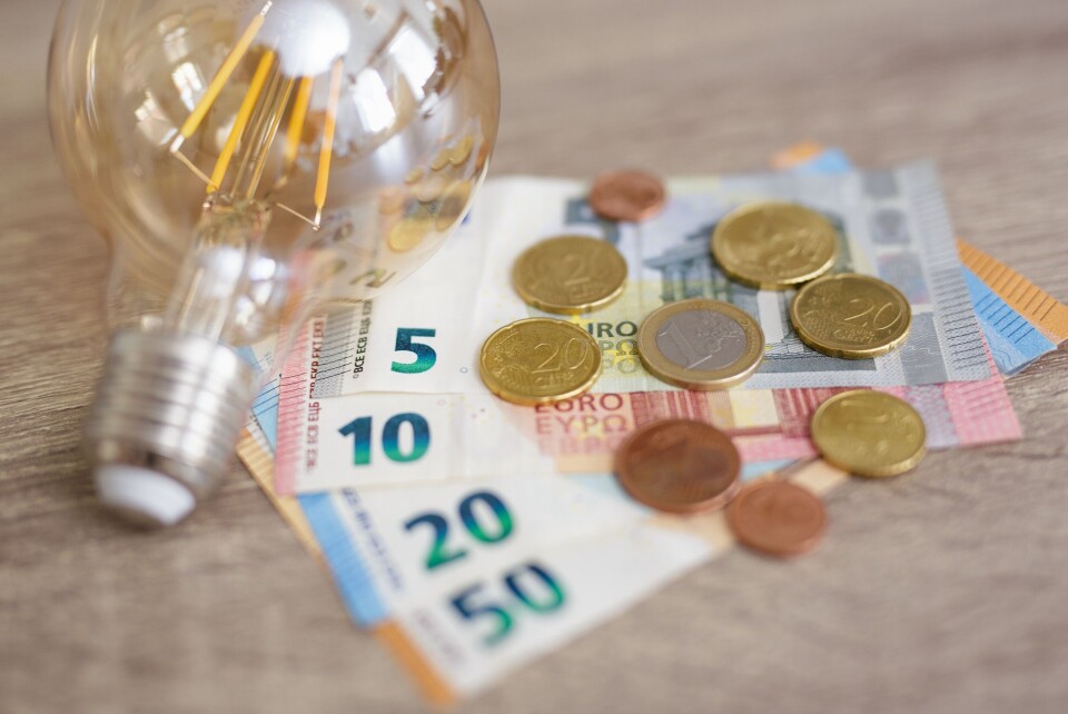 An image of a lightbulb sitting atop a pile of euro coins and notes