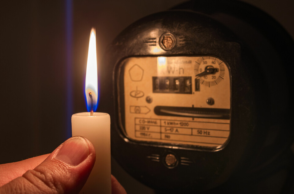 A photo of an electricity meter in the dark, with someone holding a candle in front of it