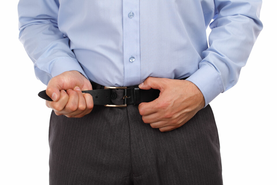 An image of a man fastening his belt
