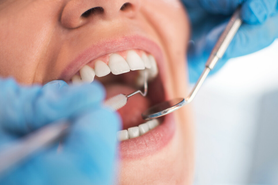 A women opens her mouth during a dentist check-up, with dentist instruments being used
