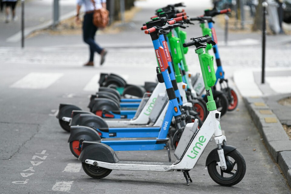 A photo of a line of e-scooters from various for-hire brands on a street in Paris