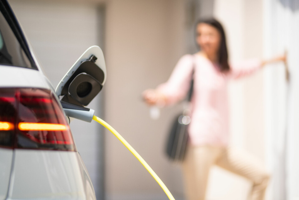 A photo of a woman entering her home as she locks an electric car charging outside
