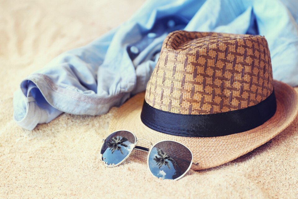 A view of a hat, shirt, and sunglasses on a sandy beach
