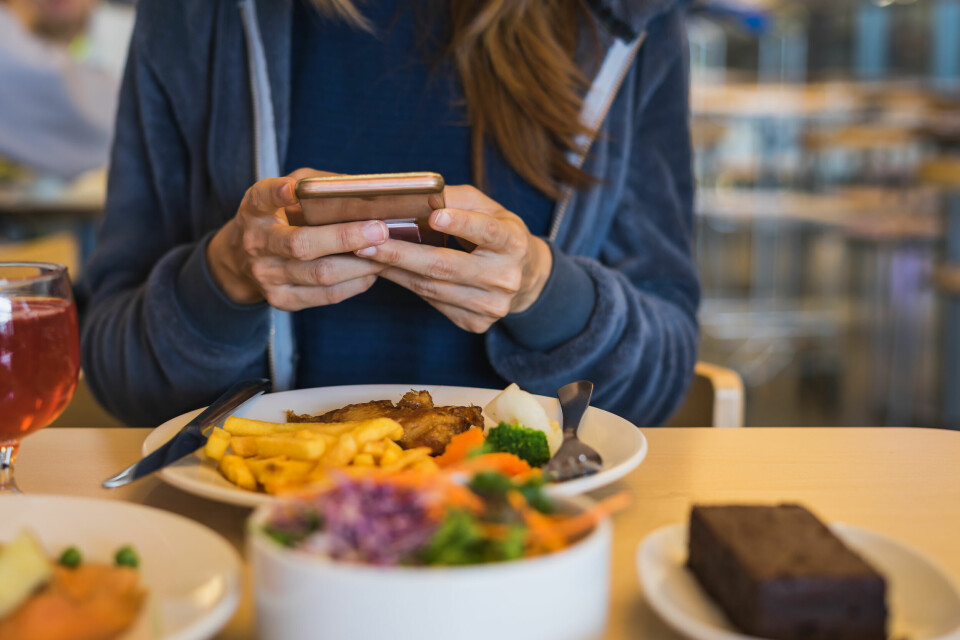 A photo of a woman using her phone while having a meal