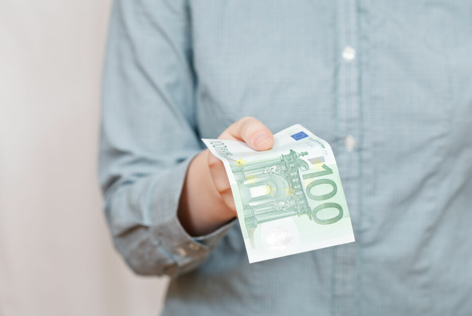 A man holds out an €100 banknote
