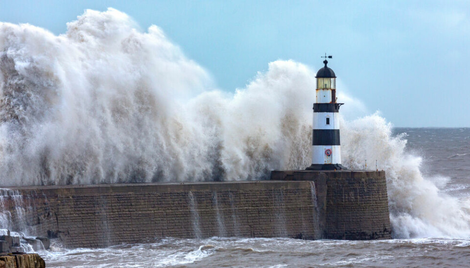 Waves hit a lighthouse jutting out on the French coastline