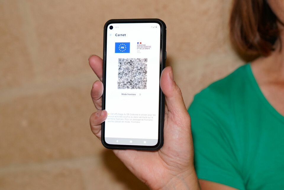 A woman holds up a vaccine pass QR code on her smartphone