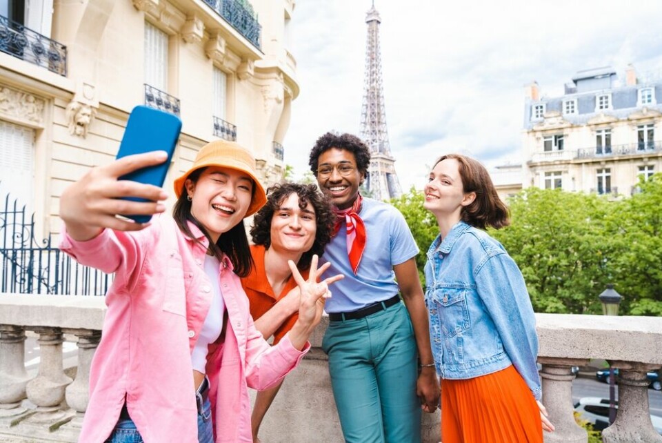 A group of friends visiting Paris and taking a selfie in front of the Eiffel Tower