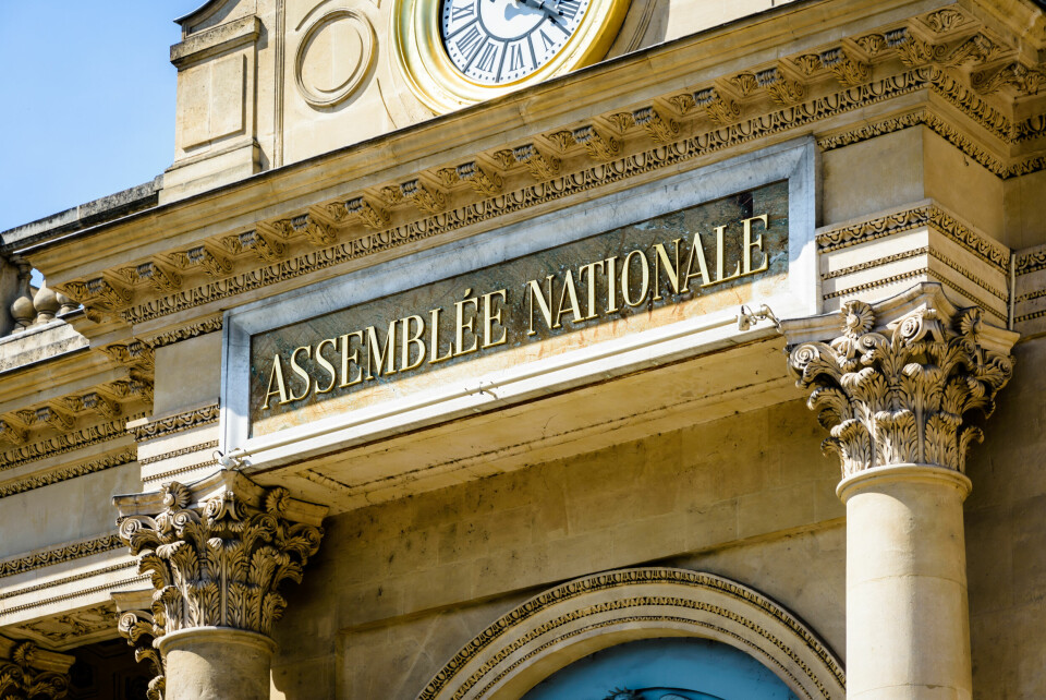 Close-up view of the sign 'Assemblee Nationale' in golden letters at the entrance of the Palais Bourbon, seat of the French National Assembly in Paris, France