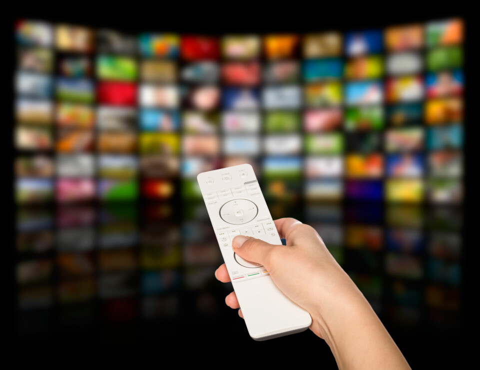 A photo of someone holding a remote with TV screens behind to show streaming platforms