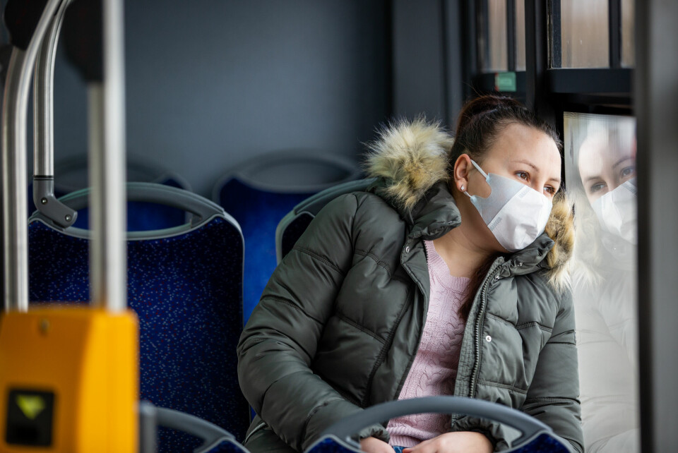 A photo of a woman on a bus wearing a face mask