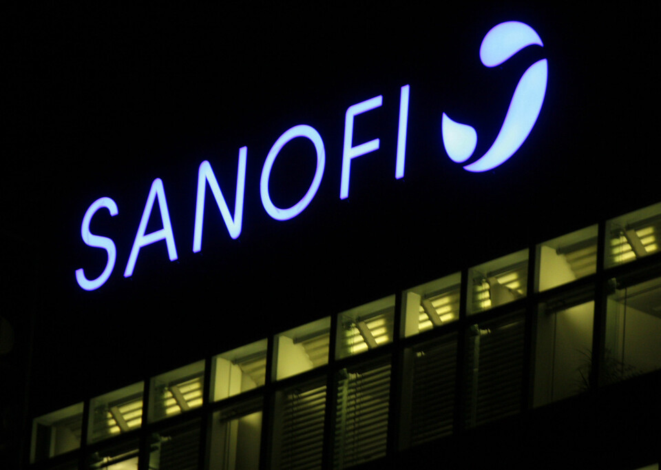The logo of the brand Sanofi lit up on a building at night