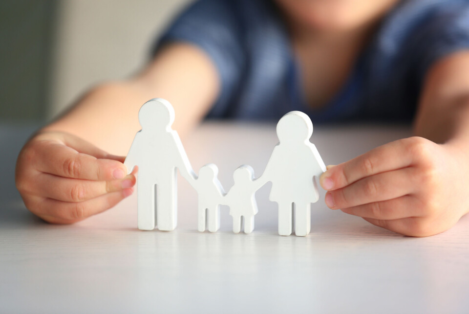 A child holds a wooden model in the shape of a traditional nuclear family