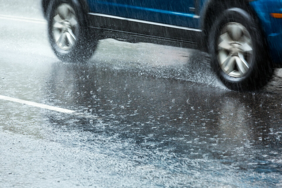 An image of a car splashing through surface water on a road