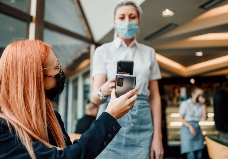 DuxX / Shutterstock A person shows a vaccine pass in a cafe