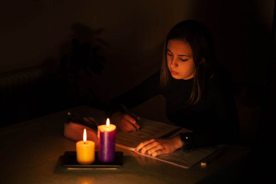 A photo of someone holding a candle up to an old-fashioned electricity meter