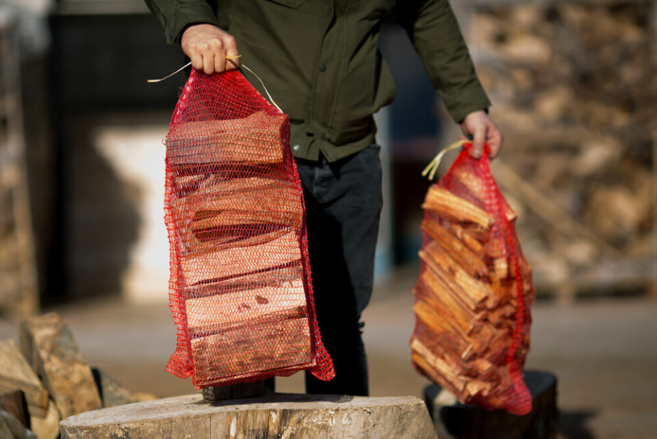 A photo of a man carrying logs in plastic wire bags