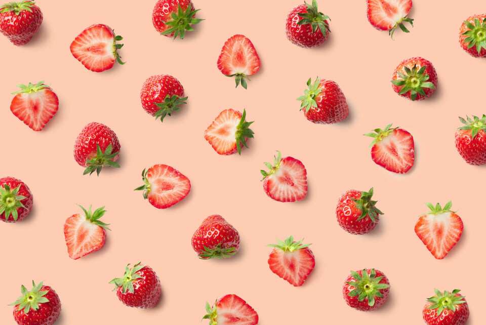 Strawberries sliced on a pink graphic background. Ramener la fraise is a French way to say being nosy.