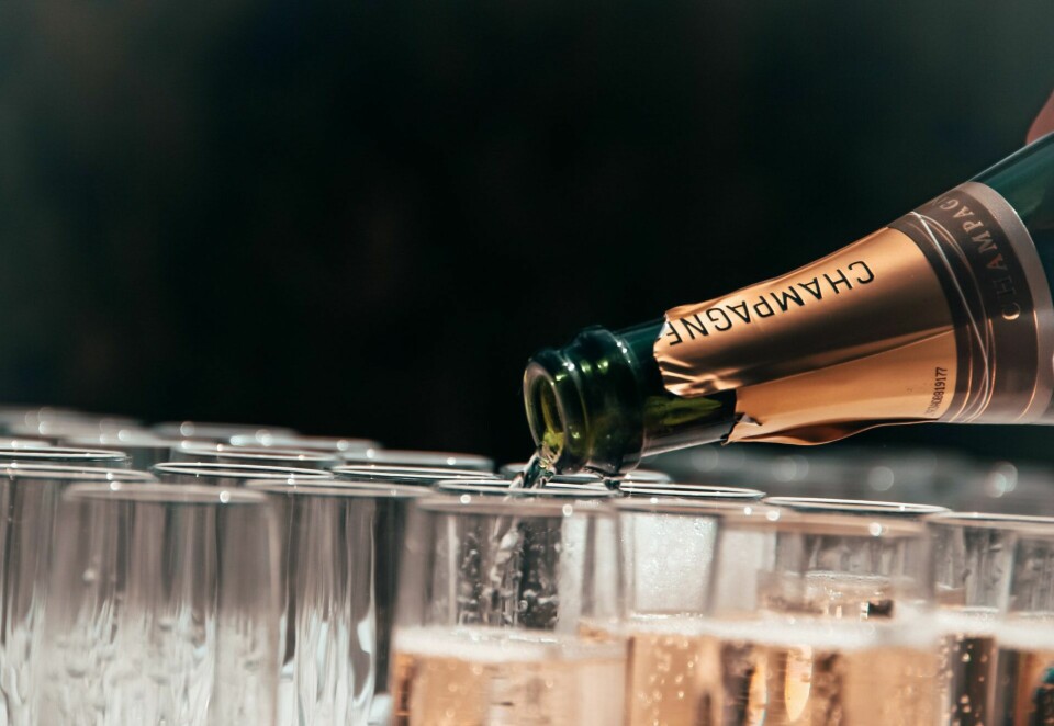 A Champagne bottle pouring into several glasses