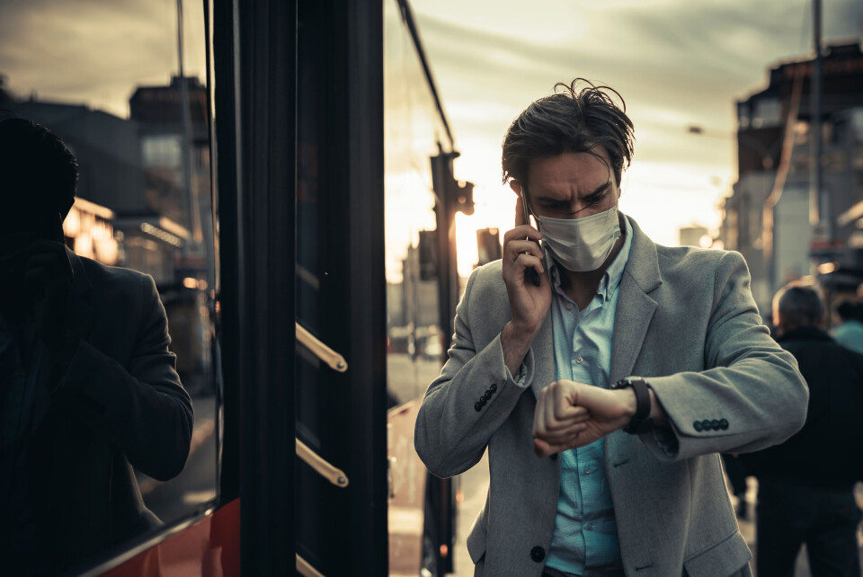 A man with a facemask checks his watch