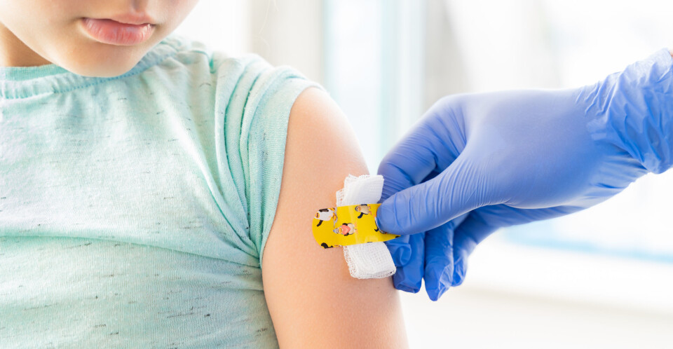 A nurse applies a plaster to a young girl’s arm after an injection