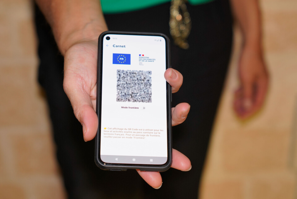 A woman holds out a health pass on a smartphone