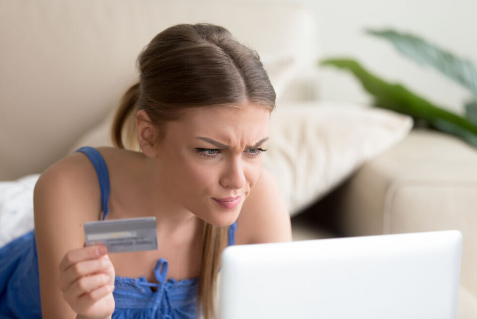 Fizkes / Shutterstock A woman sits at the computer with a credit card considering a possible scam