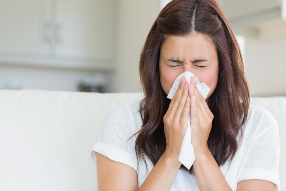 An image of a brunette woman blowing her nose