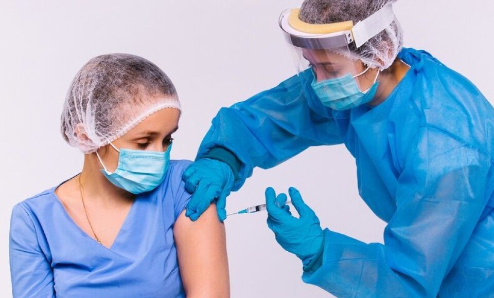 PixelsMD Production / Shutterstock A doctor in protective gear, a medical mask and a screen gives another female doctor a vaccine for Covid 19.Reaction: France mandatory vaccine plan covers 1.5m workers in 70 jobs