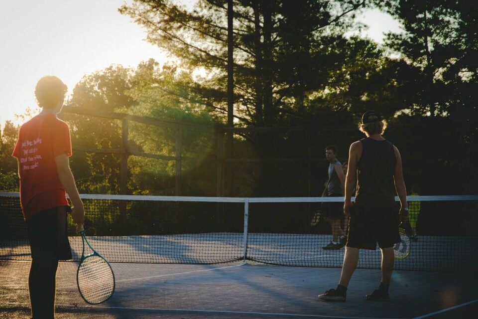 A group of people play tennis outside in a court. France lockdown: You can now go beyond 10km for (some) sport reasons