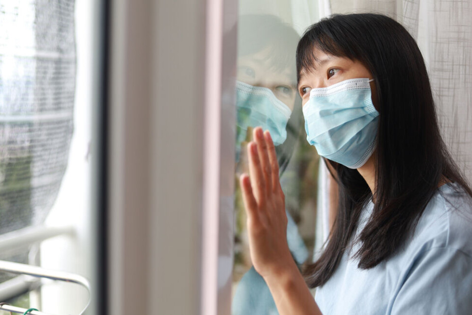 TY Lim / Shutterstock A woman quarantining at her home stares out of a window
