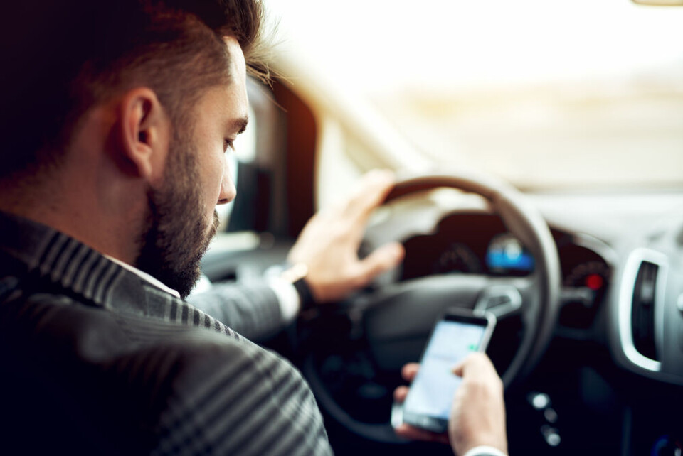 A man using a mobile phone while driving. France tests speed cameras that also check phone and seatbelt use