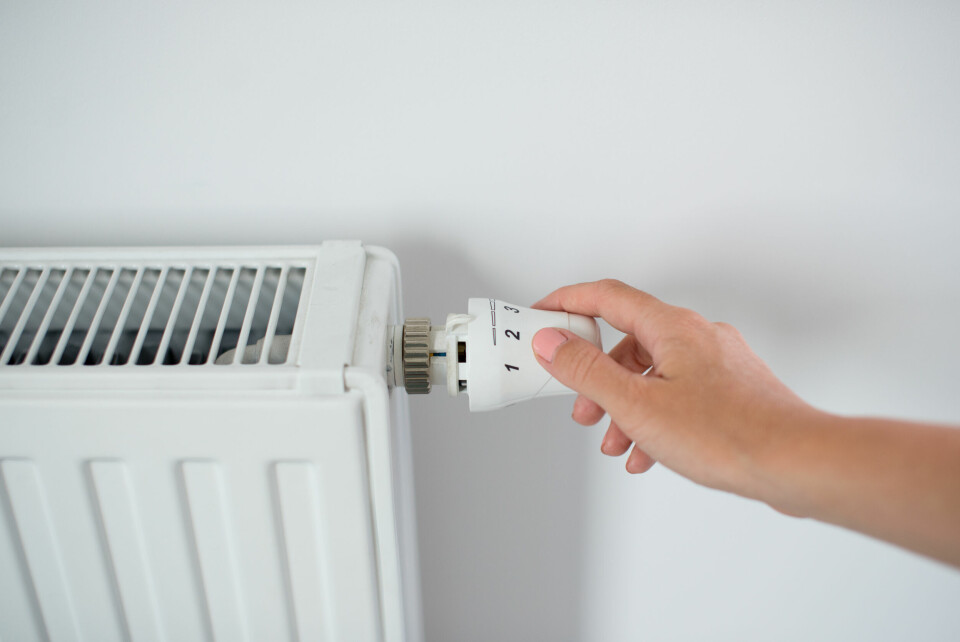 An image of a woman's hand adjusting the temperature on a radiator