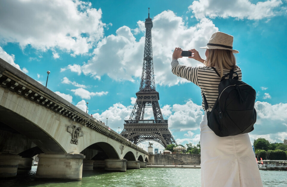 Andrey Yurlov / Shutterstock A tourist in Paris takes a picture
