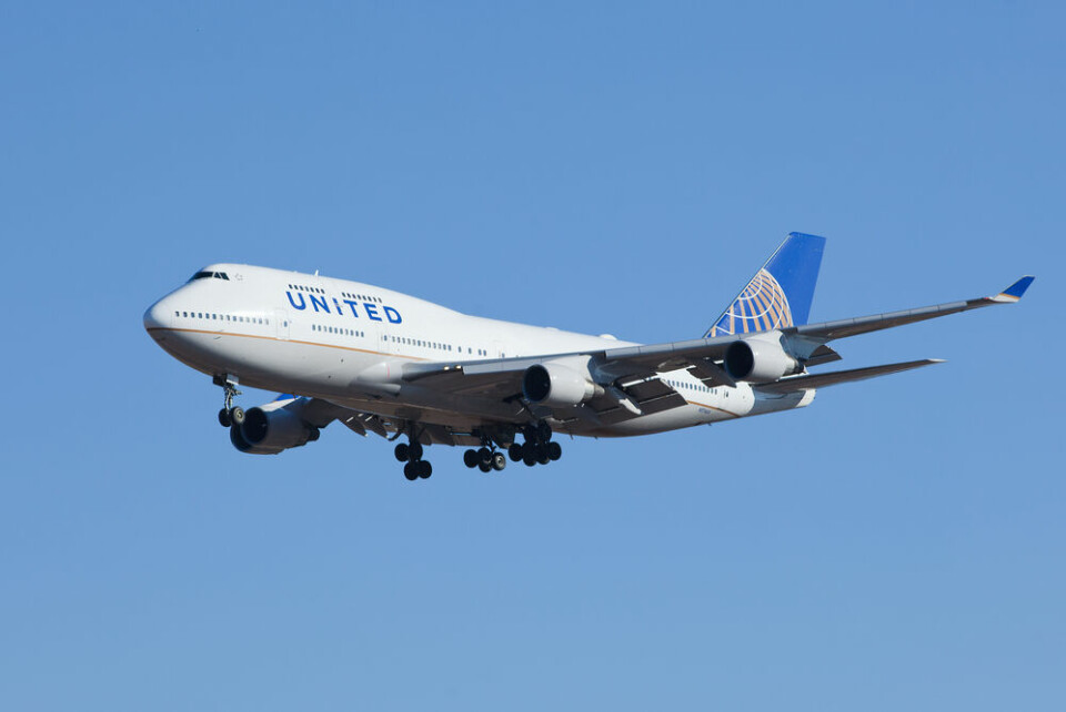 United Airlines plane flying through blue sky. New report on error causing near runway collision of US plane in Paris
