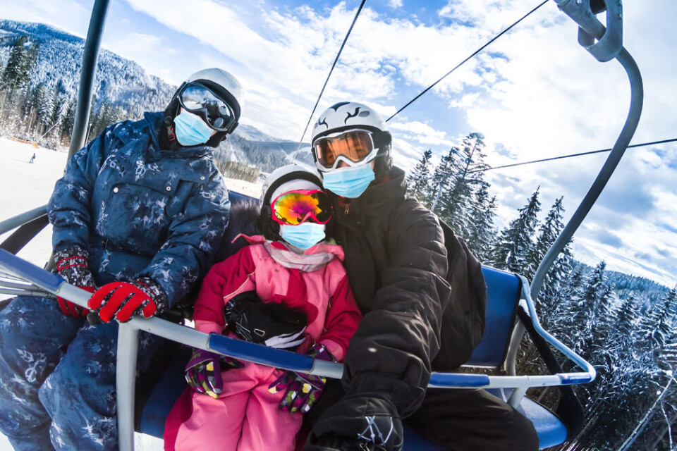 Andrew Angelov / Shutterstock A family wearing masks while skiing