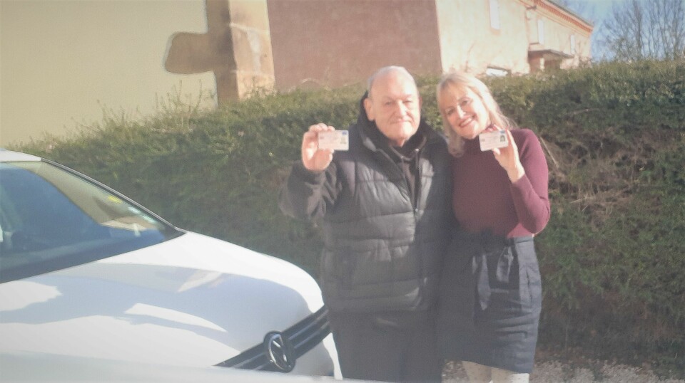 An image of Bob and Trisha Street standing by their car holding UK driving licences