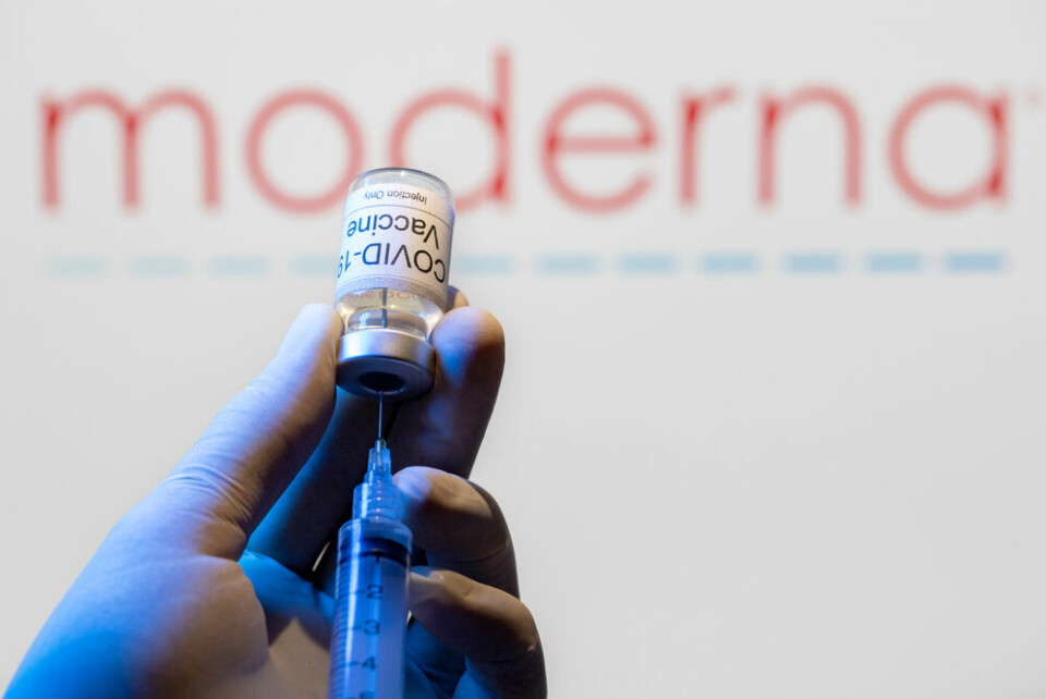 A hand preparing a dose of the Moderna vaccine with the logo behind it. Covid France updates June 2: Moderna jab, holiday vaccines and more