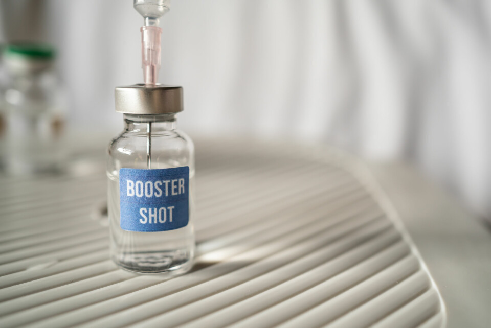 A syringe in a vial of liquid labelled ‘Booster Shot’