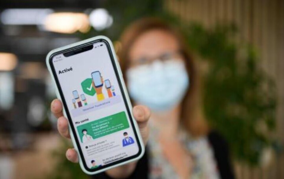 A woman holding a smart phone with Covid data on it. French MPs vote in favour of Covid health pass for use from June 9