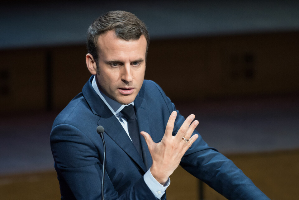 President Emmanuel Macron making a speech, holding up five fingers