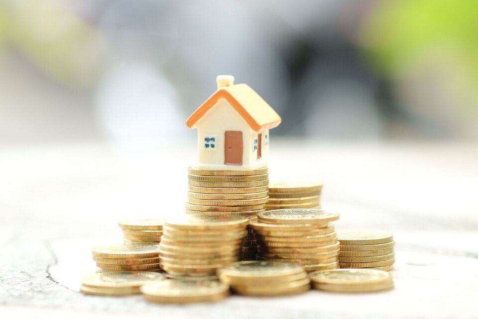 A mini house model sitting on a pile of coins