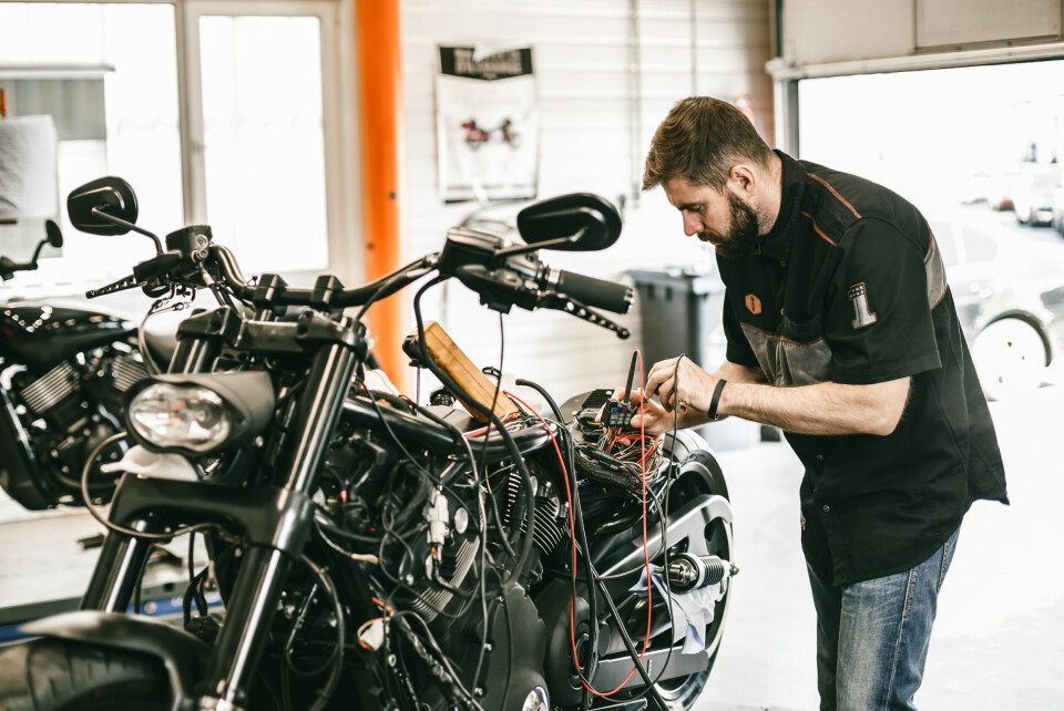 An image of a man repairing a motorbike in a garage