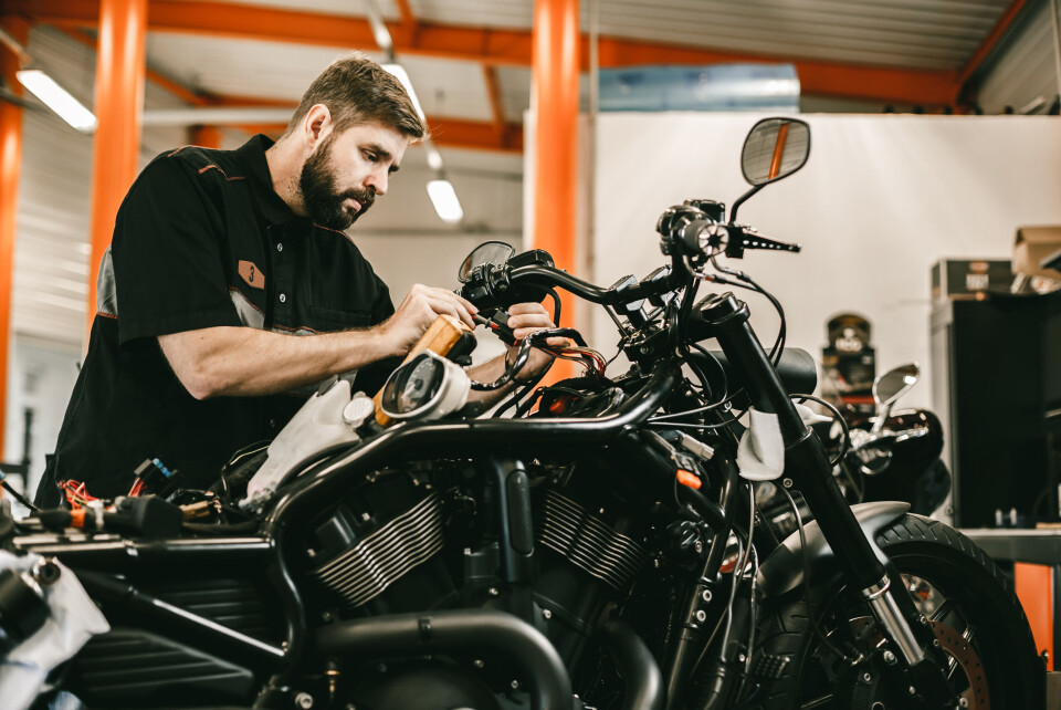 A picture of a man repairing a motorbike