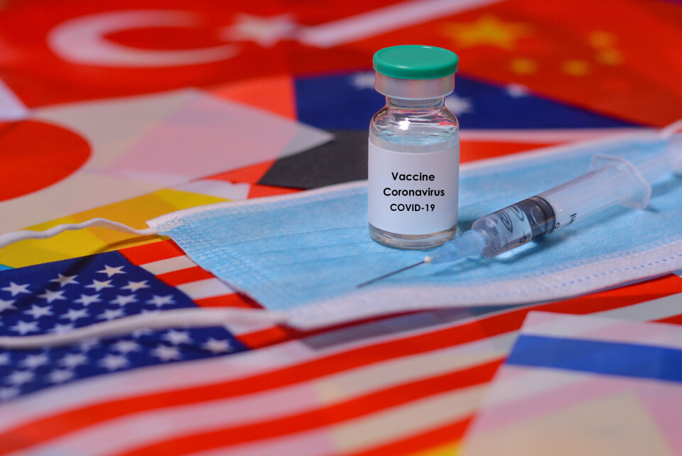 StanislavSukhin / Shutterstock Medical mask, coronavirus vaccine bottle, syringe against the background of the flags of the countries of the world.