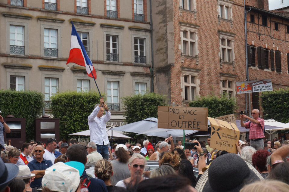 A protester wields a three-coloured French flag in the middle of the crowd, at the demonstration against sanitary passport and vaccine mandate for health workers. 160,000 protest against health pass rules in France