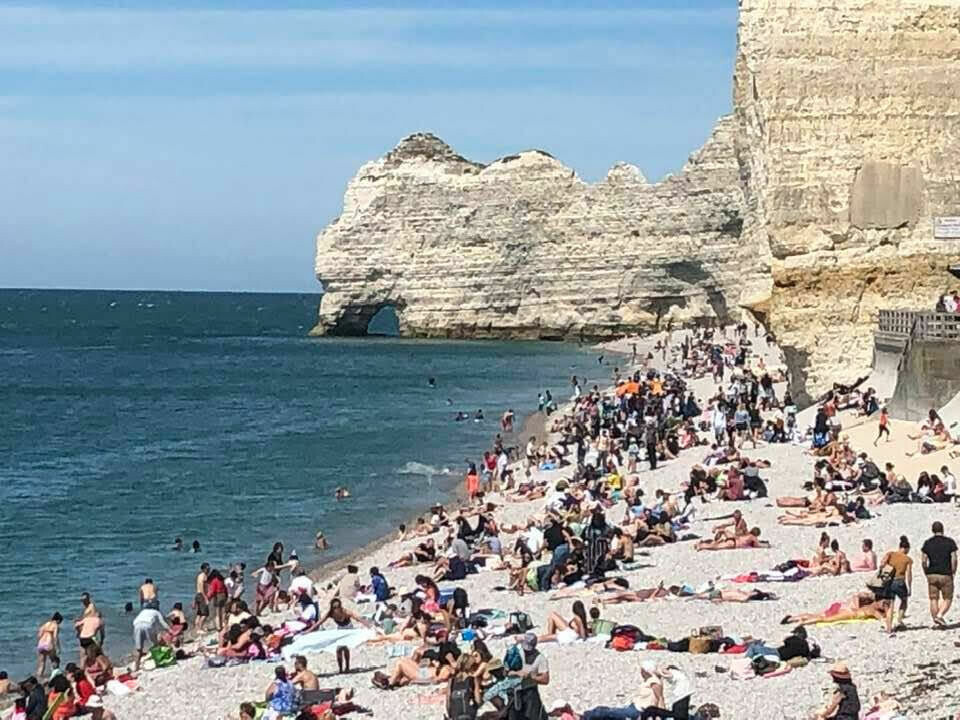 An image of the beach in Etretat, Normandy, full of tourists